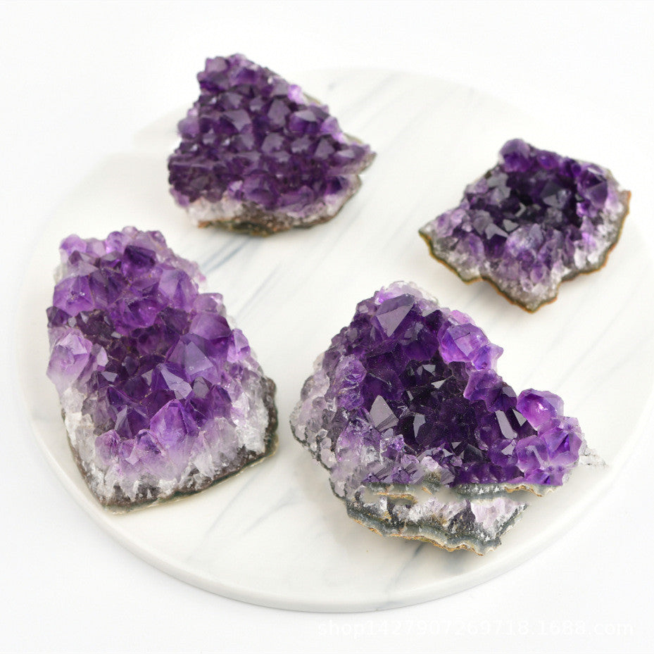 Four purple amethyst crystals on a white plate