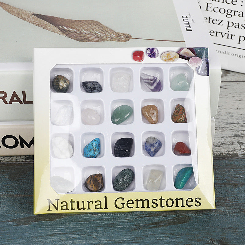 Box of natural gemstones with a variety of stones on a wooden surface.