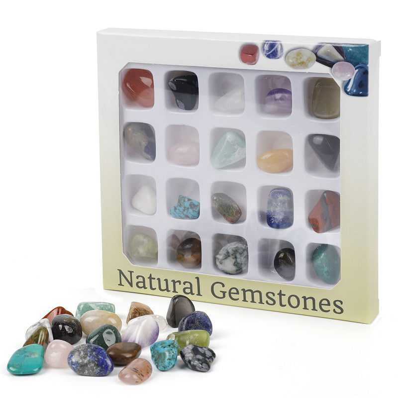 Box of natural gemstones with a variety of stones displayed on a white background