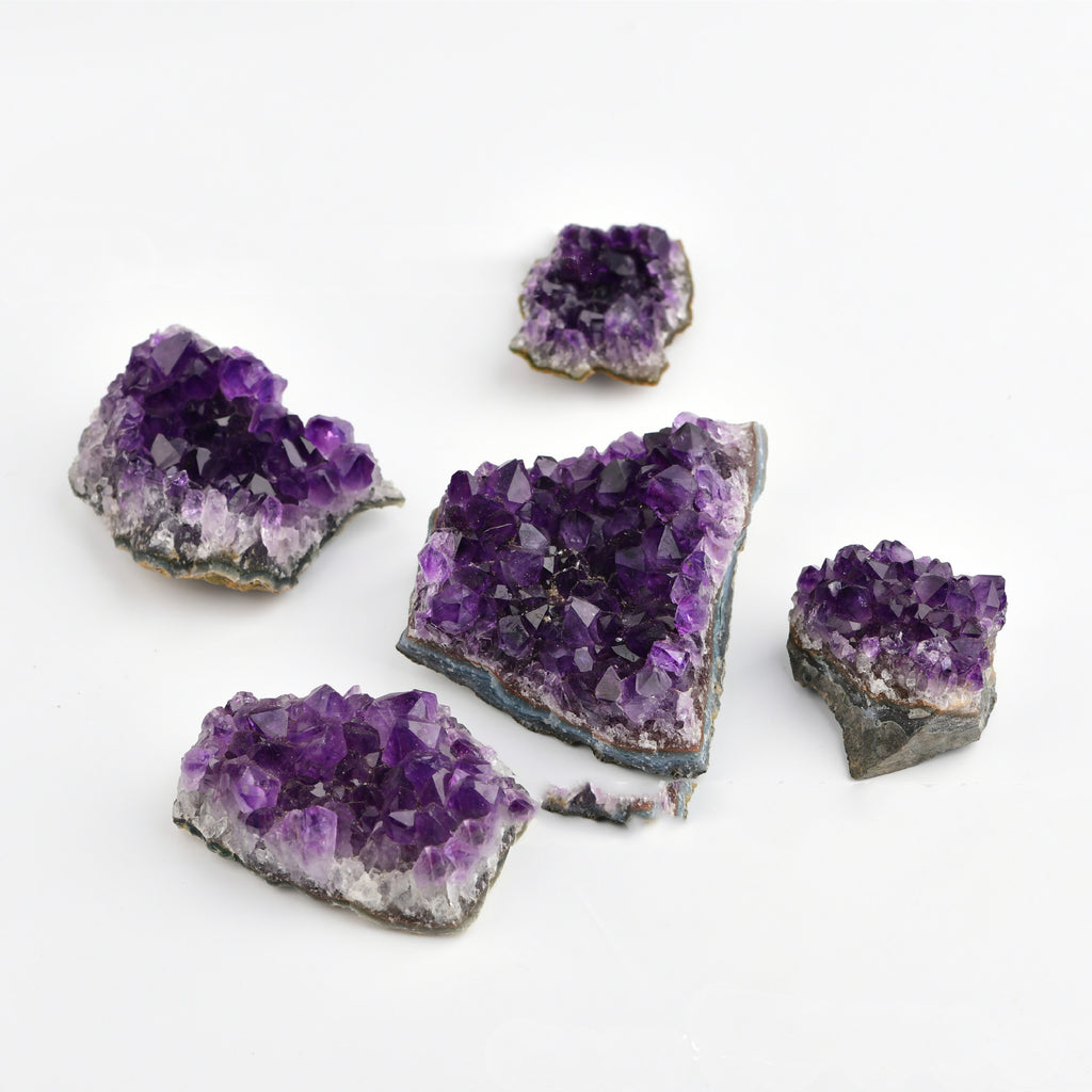 Five purple amethyst geodes on a white background