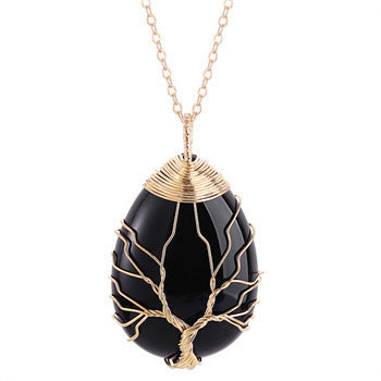 Black stone pendant with gold wire wrapping on a chain against a white background